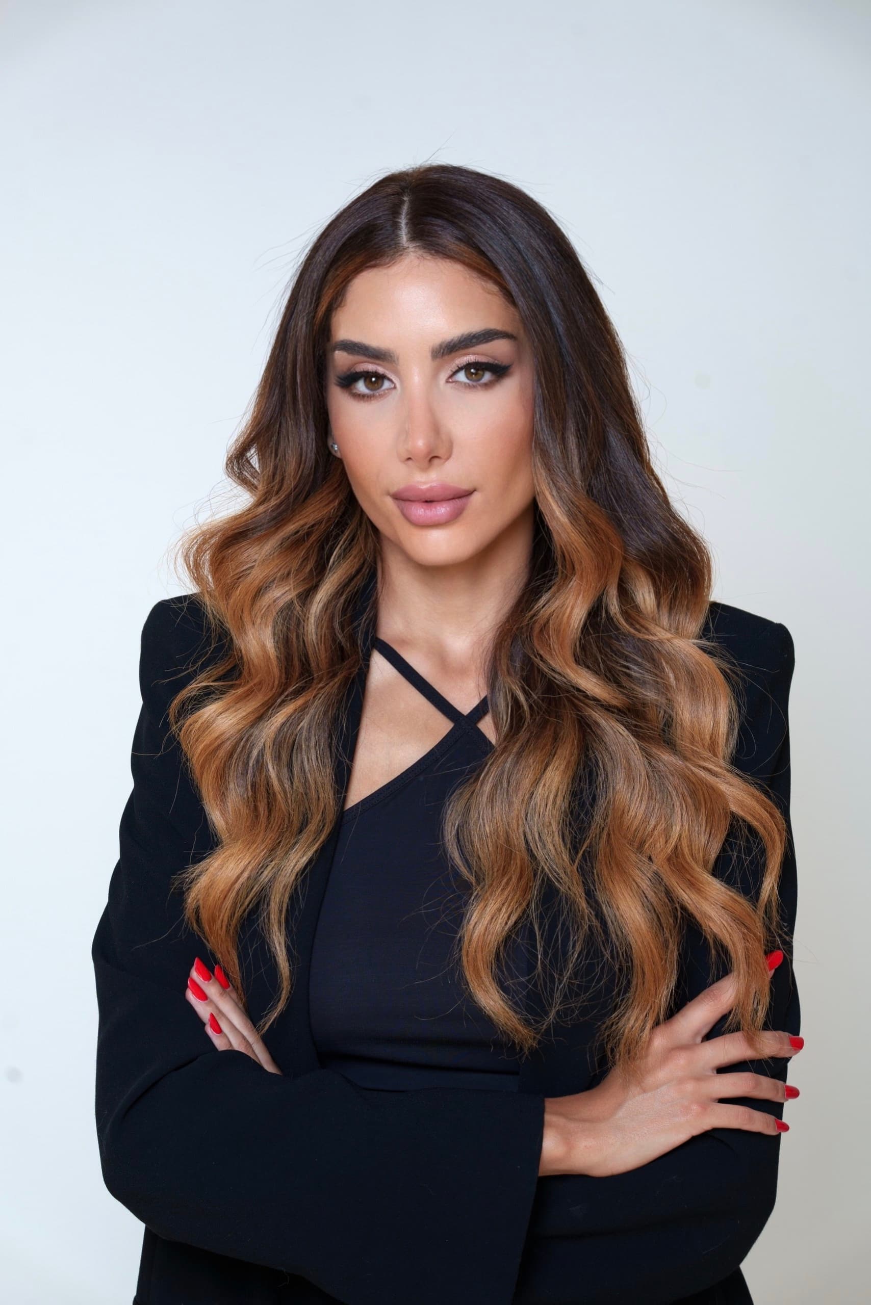 Amira Bechini in the studio, in a black blazer, arms folded, against a pale ground.